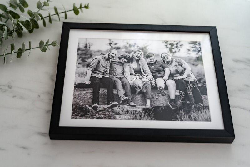 A black and white photo mounted on a thin, foam-backed board rests on a marble table.