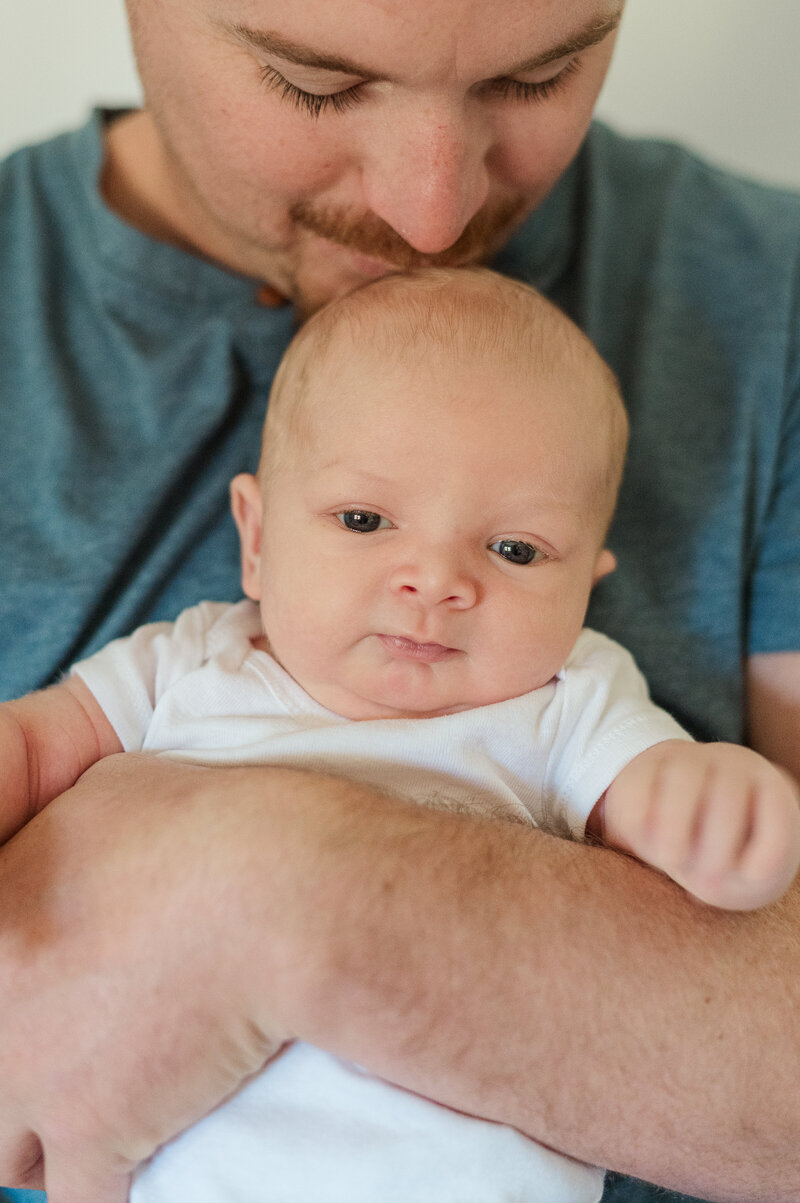 father holding newborn baby against his chest looking out by york pa photographer