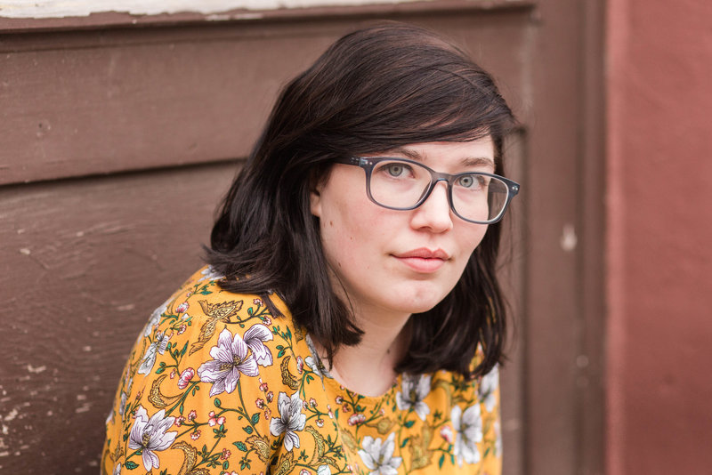 waynedale high school senior girl wearing mustard yellow top with white flowers on it with brown door behind her, photographed by Jamie Lynette Photography Canton Senior Photographer