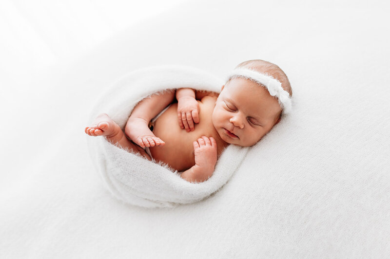 Newborn baby girl swaddled with white headband