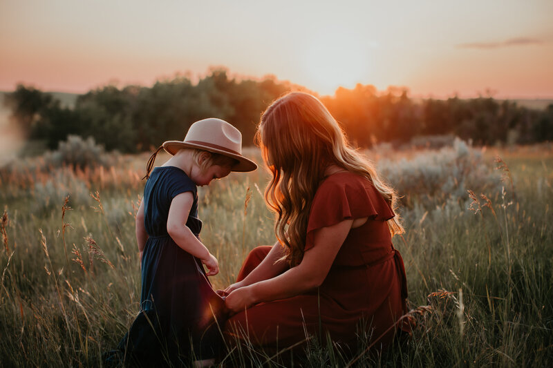 A heartwarming family portrait taken in Vida, MT. The photo captures the love and bond between a mother and child, set against the golden tones of the Montana sunset, creating a peaceful and intimate moment in nature.