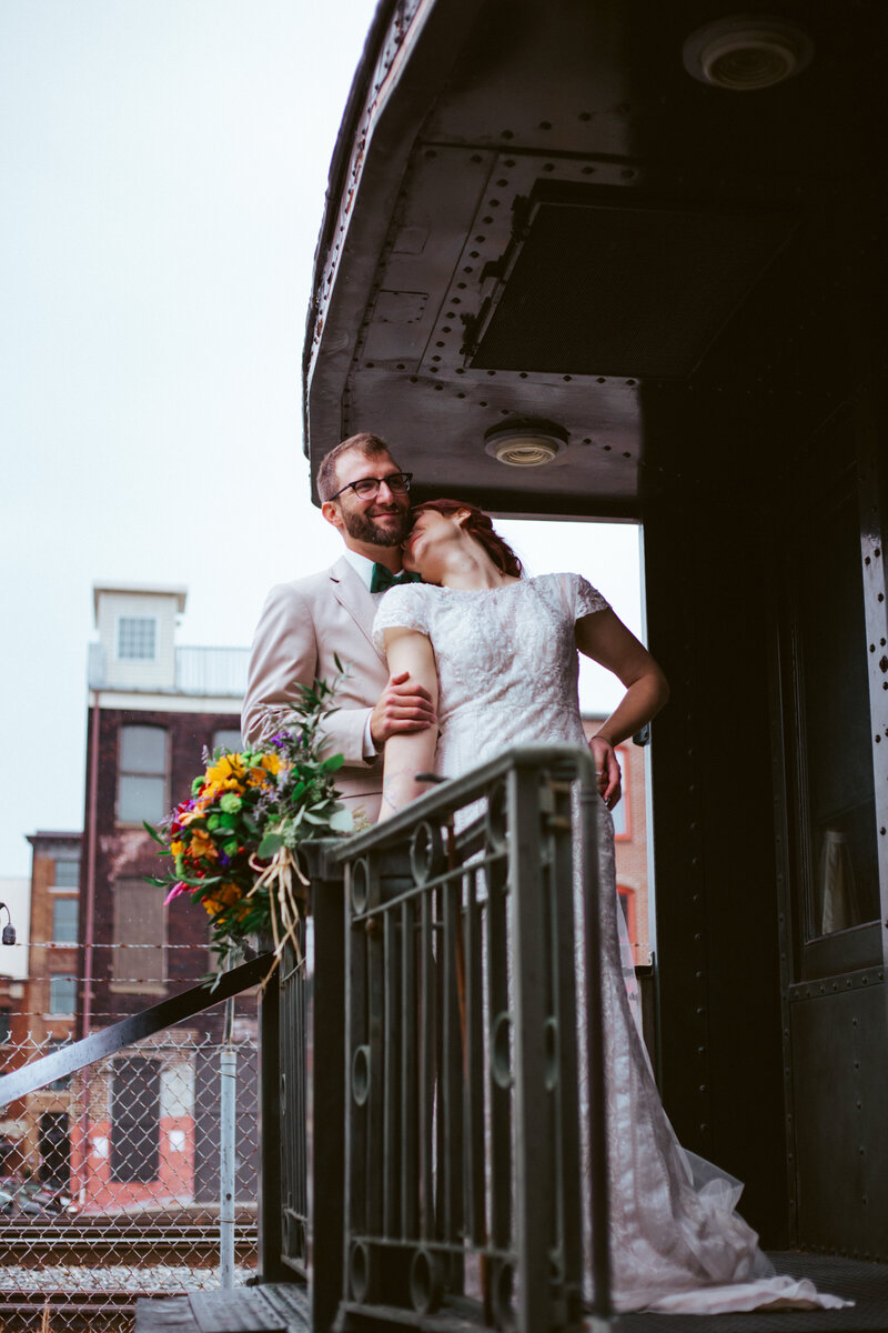 bride kissing groom on the back of a train