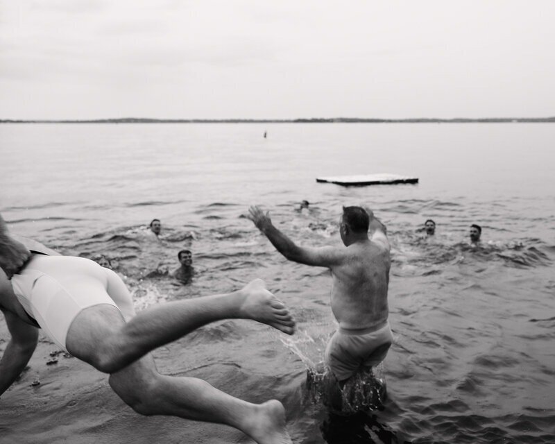 black and white photo of people jumping into water to swim taken by tom thornton photography