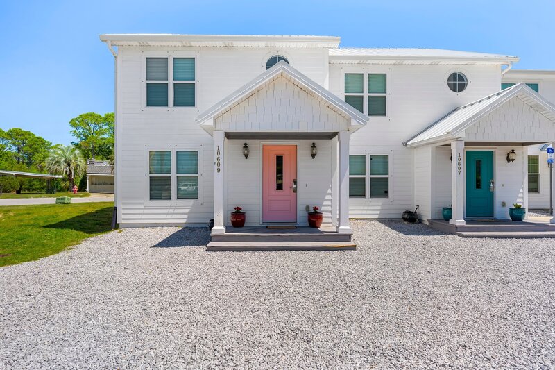 Charming front exterior of the Surf House with a pink door, located in a peaceful neighborhood near the beach.