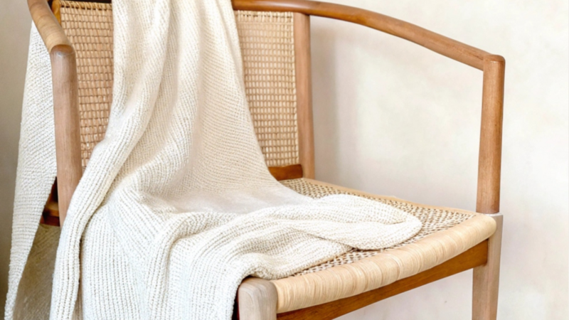 ratton armchair with a white blanket draped over it