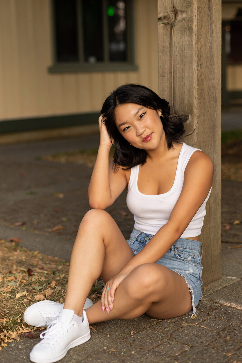 urban senior photos, seated and leaned against a wooden post
