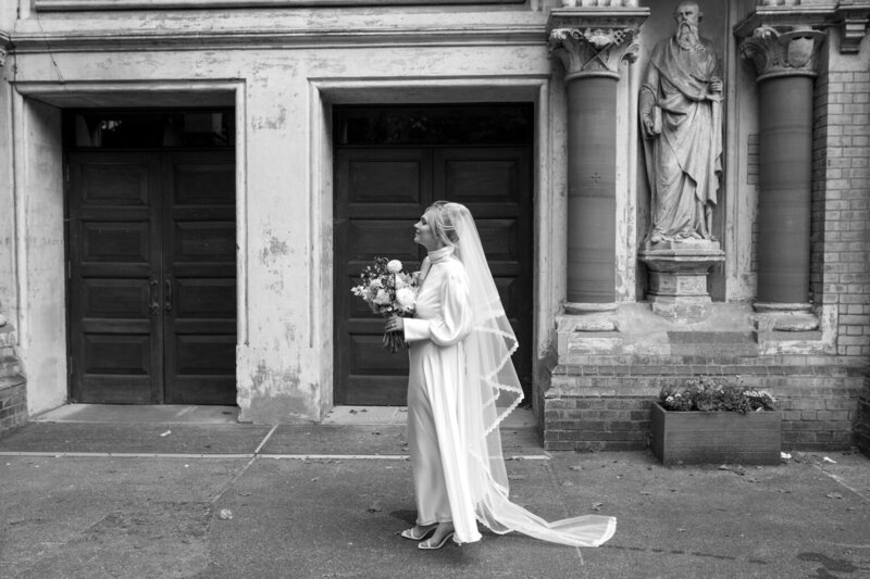 Chic allure: Bride walking from church to reception in a black and white image.