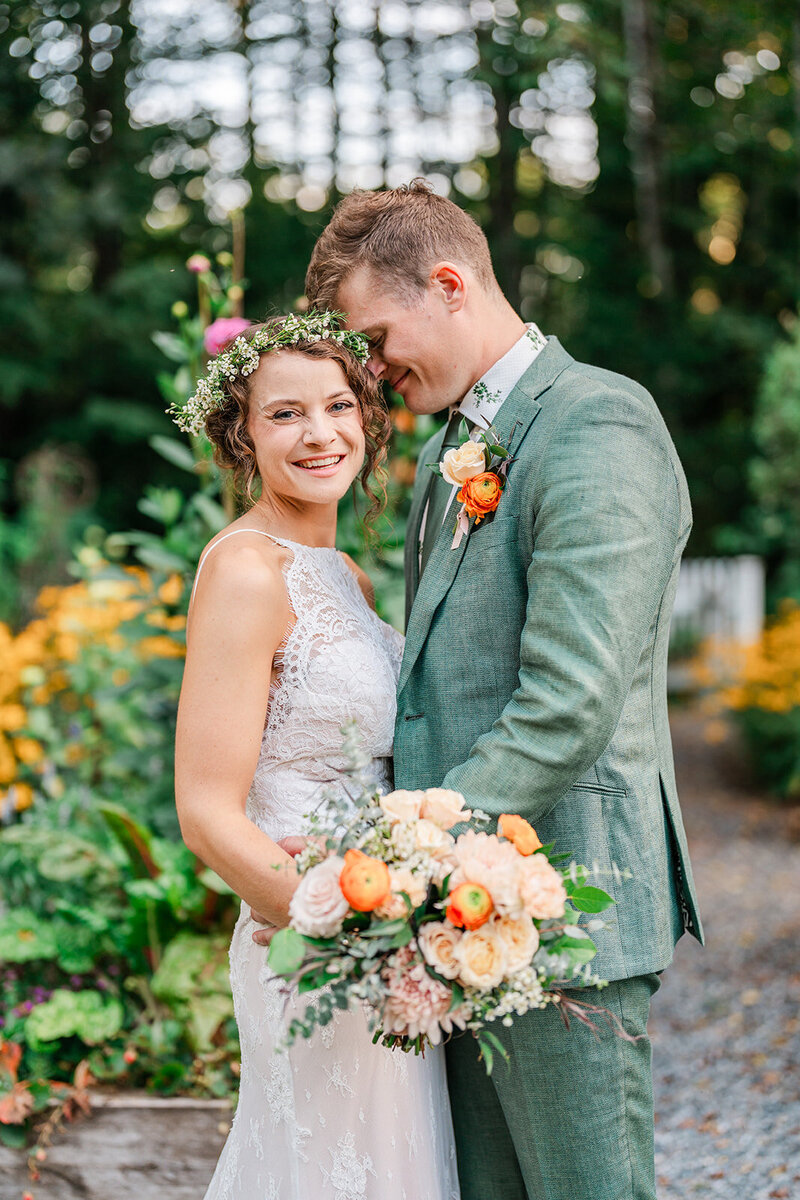 A couple posing for newlywed photos in a garden after their Maine elopement.
