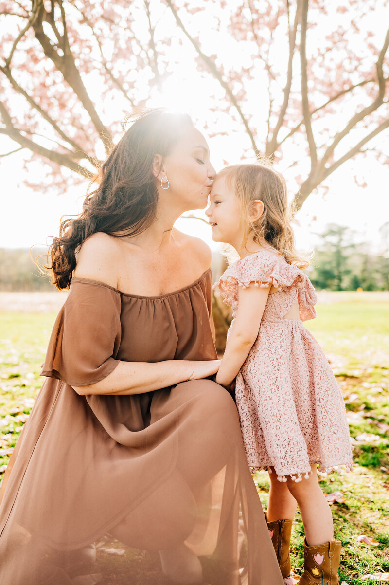 Couple in field, looking down at pregnant mom's belly