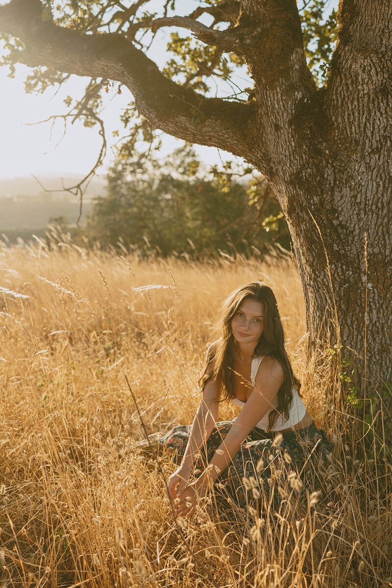 girl wearing black cowgirl hat and black tank top and sitting in grassy field