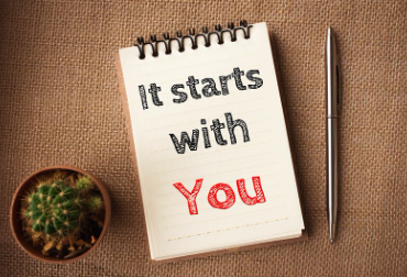 A pen beside a notepad with 'It Starts With You' on the front, reflecting how you can decide to begin the coaching journey