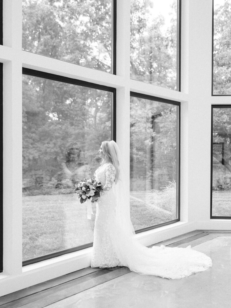 black and white bridal portrait with bride looking out tall windows at Osage House in Arkansas