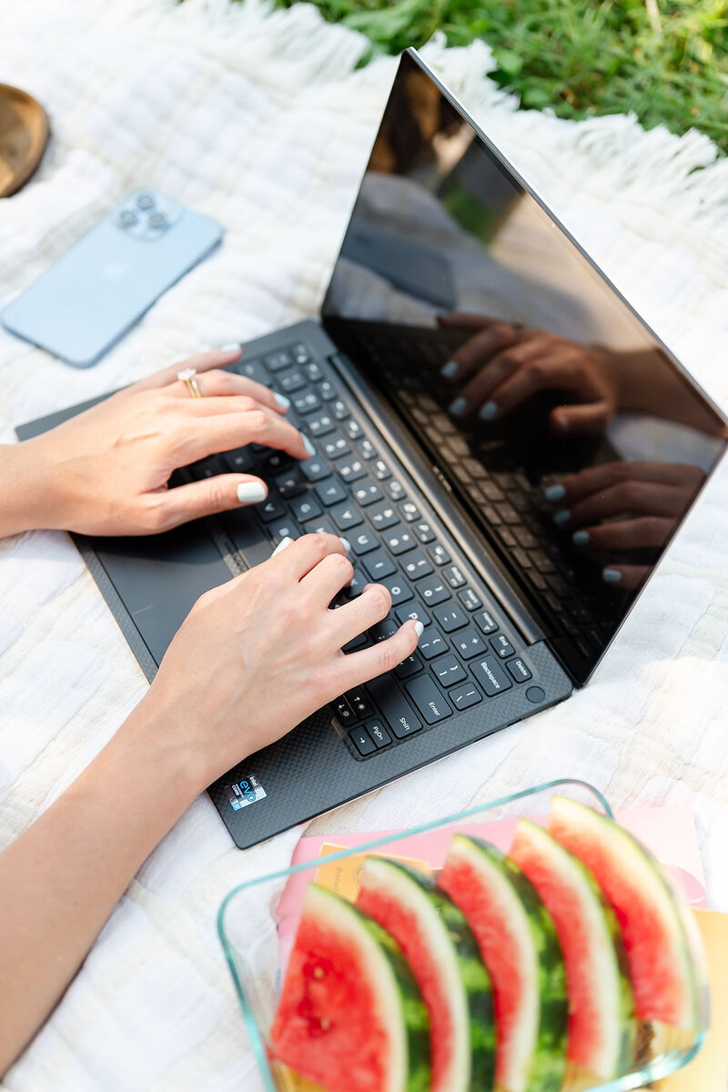 Flat lay of a person working on a computer on a picnic blanket