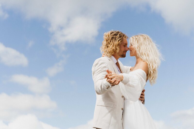 bride and groom share a hug with open blue charlotte skies behind them