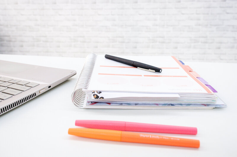 notebook and laptop on a white desk with pens and markers