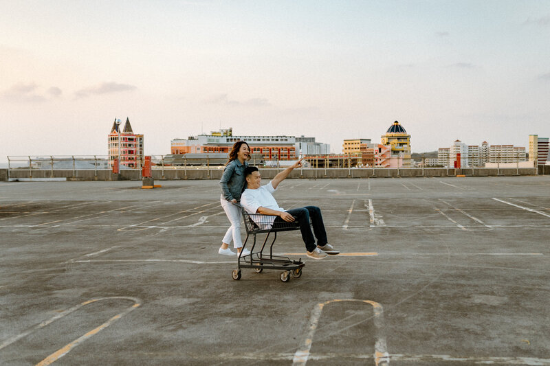 J pushing J in a shopping cart on a rooftop