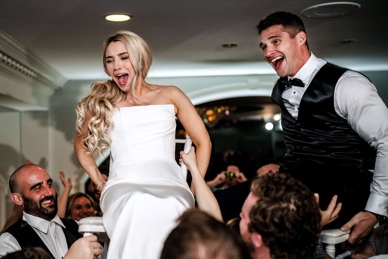 A candid, heartfelt moment by the Connecticut shore, with the bride laughing joyfully, nestled in the groom's embrace, under a soft sunset sky — a perfect capture by a Connecticut wedding photographer.