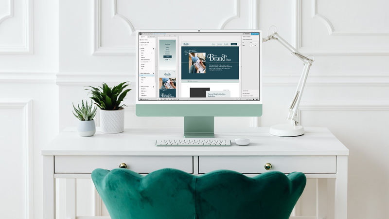 Desktop computer displaying a website design project in progress with a clean, minimal workspace and green velvet chair.