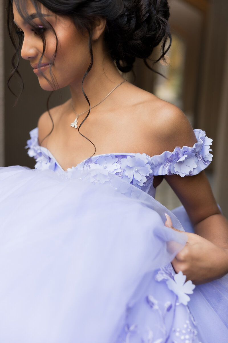 woman in quinceanera dress standing in front of large stone building