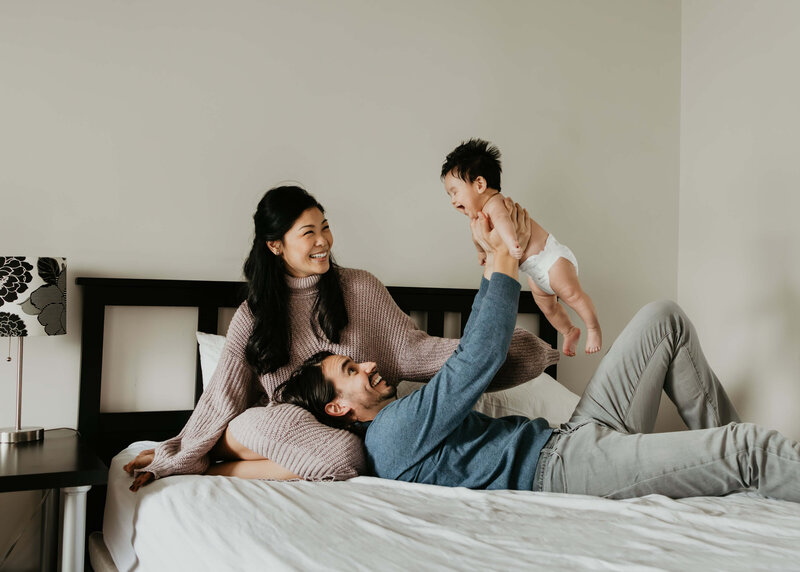 Young family relaxing on their bed at home in Pittsburgh during a lifestyle photo session