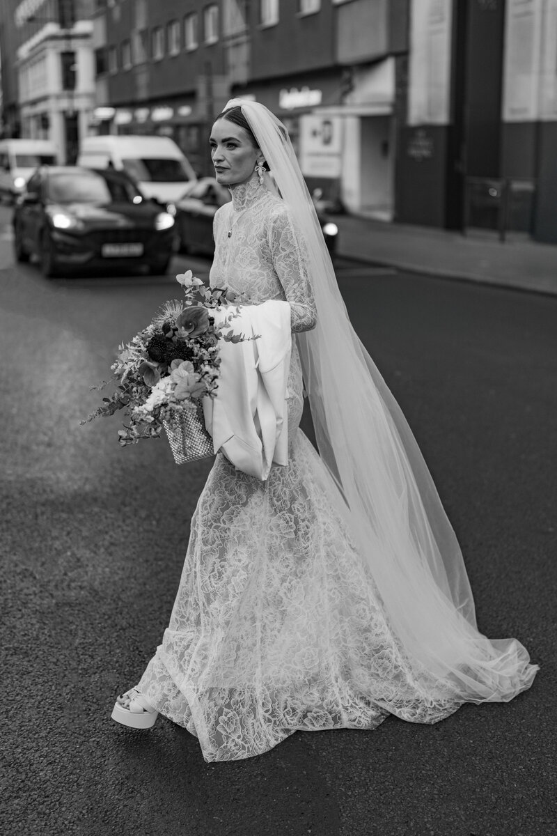 stylish bride walks across the street on the way to get married at st etheldreda's chuch in central london