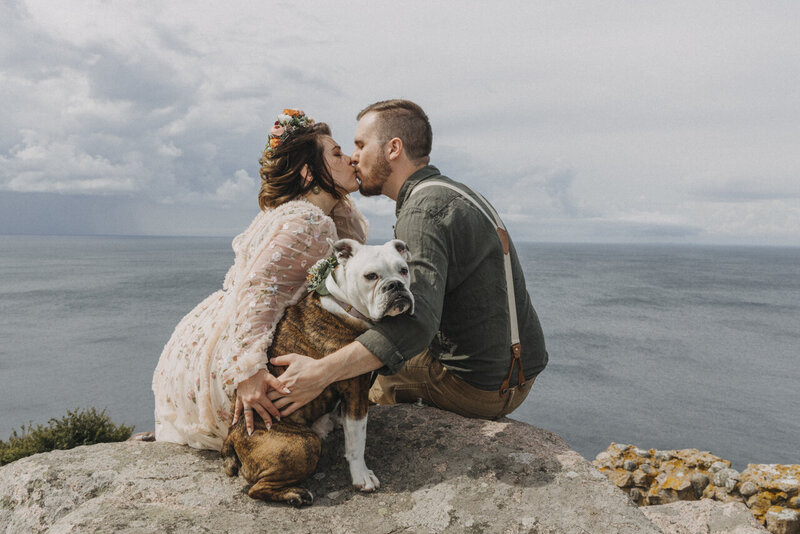 Newlyweds kissing and hold their dog, after they elope abroad and get married on Bornholm in Scandinavia