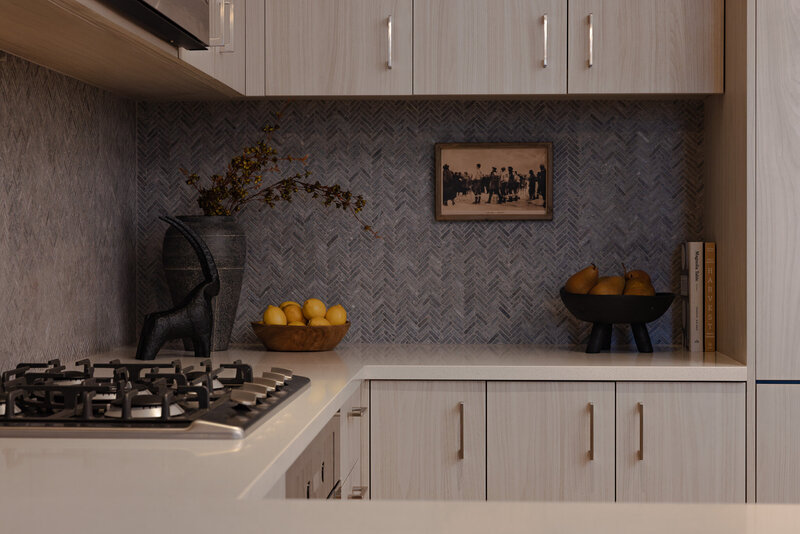 Wide view of a modern white oak kitchen with dark backsplash, styled decor, and warm tones in a Park City luxury Airbnb, designed by Sister Studio.