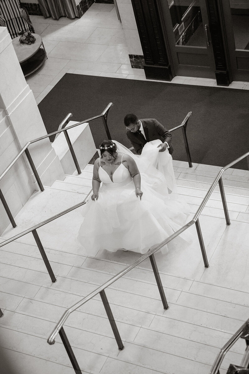 bride walking up stairs with train held wedding day