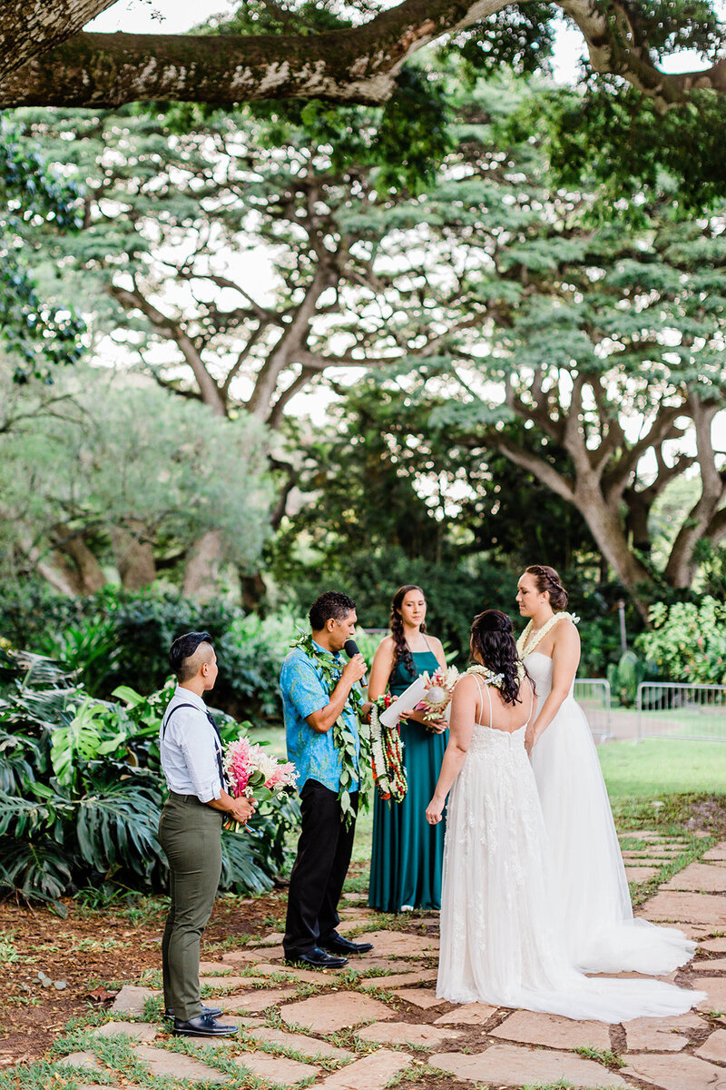 brides standing with their wedding officiant and bridesmaids during wedding ceremony