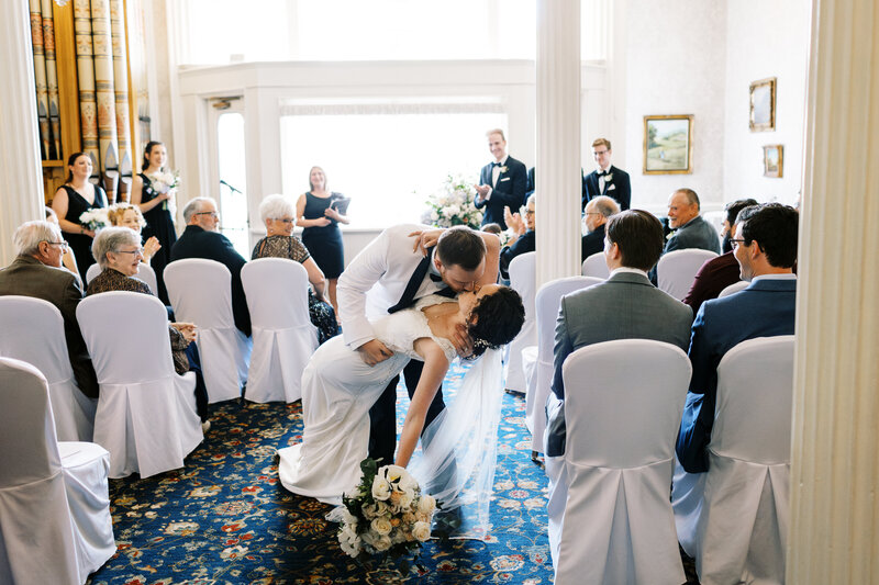 After the ceremony groom dipps his wife and kisses her while the guests cheer at St. James hotel wedding.