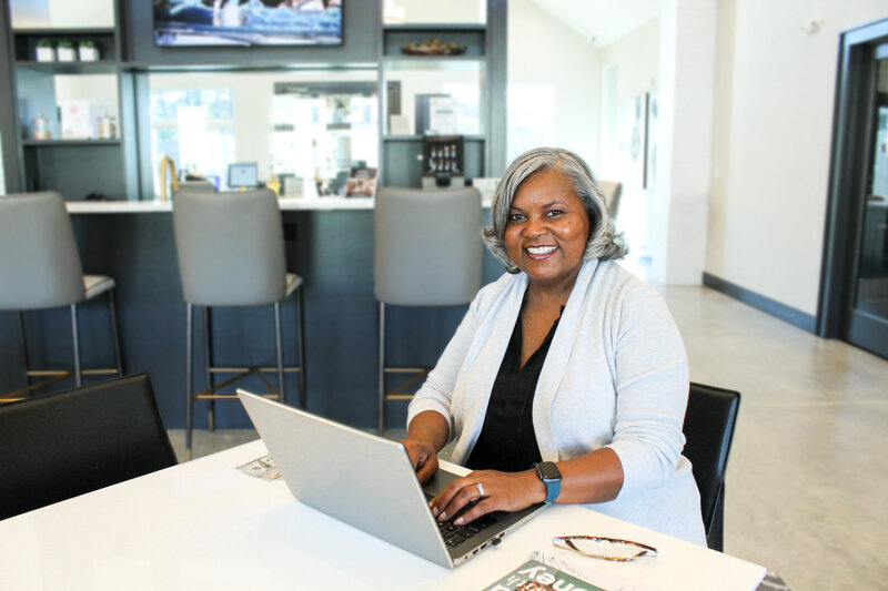 Angela smiling while working on her laptop