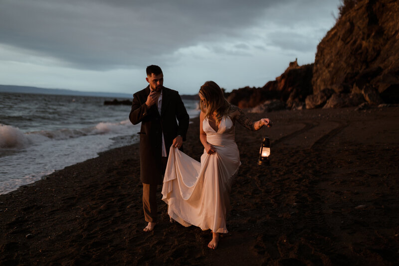 bride and groom walking on beach with lanters