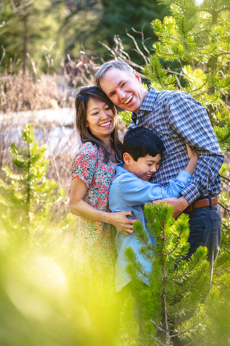 A family of three gives a big bear hug by a creek in Keystone, Colorado.