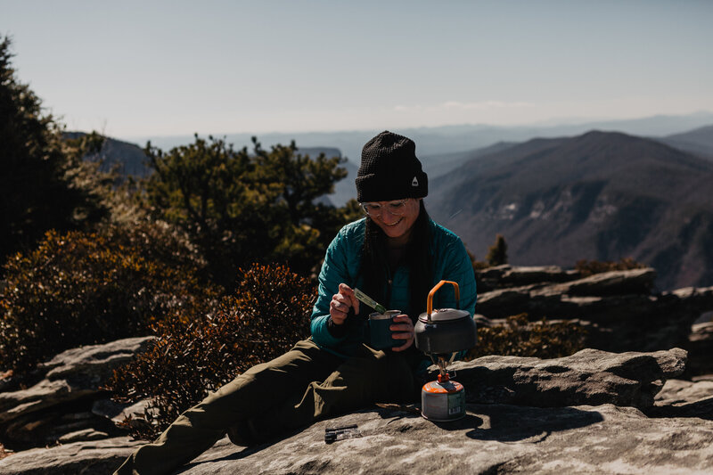 Julie Crawford is an adventure photographer making coffee on a mountain hiking trail.