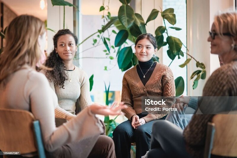 A therapist leading a group of women discussing motherhood.
