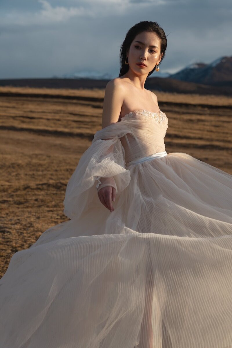 Couture dress bridal shoot on a field with mountains in the background and golden light.