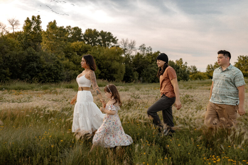 Family of four walking through a wild flower field at sunset.