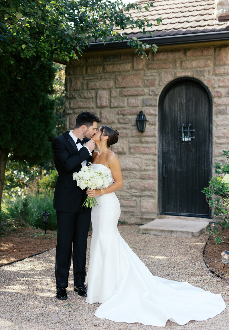 Bride and groom kissing in front of a wedding venue.