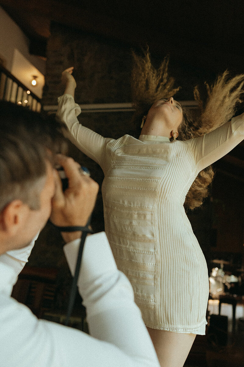 man taking photo of woman tossing hair during at home couples photos, captured by Elsie Goodman, an NYC engagement and couples photographer