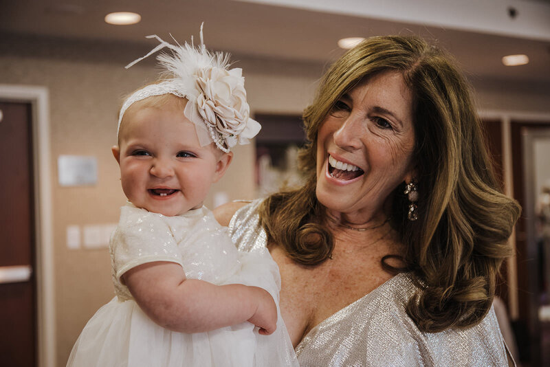 A person smiling and holding a baby
