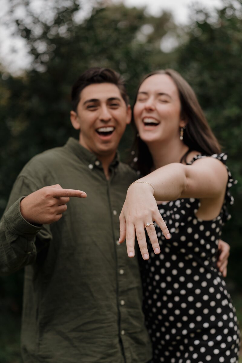 Engaged couple laughing and showing the engagement ring during a photo session in Marietta.
