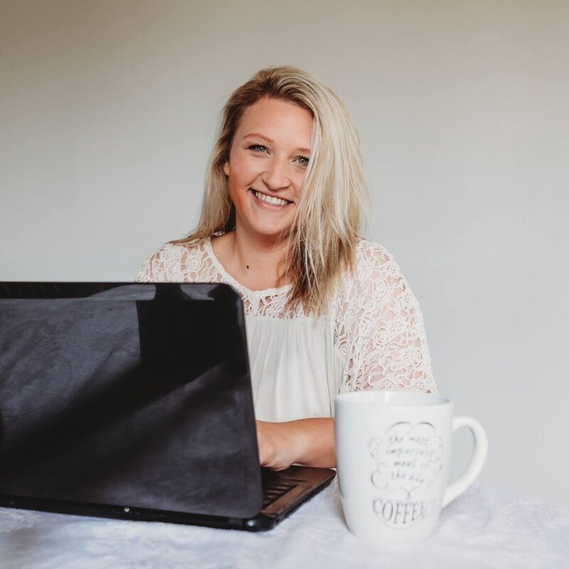 happy photographer holding a camera sitting on a couch in a newborn photography studio