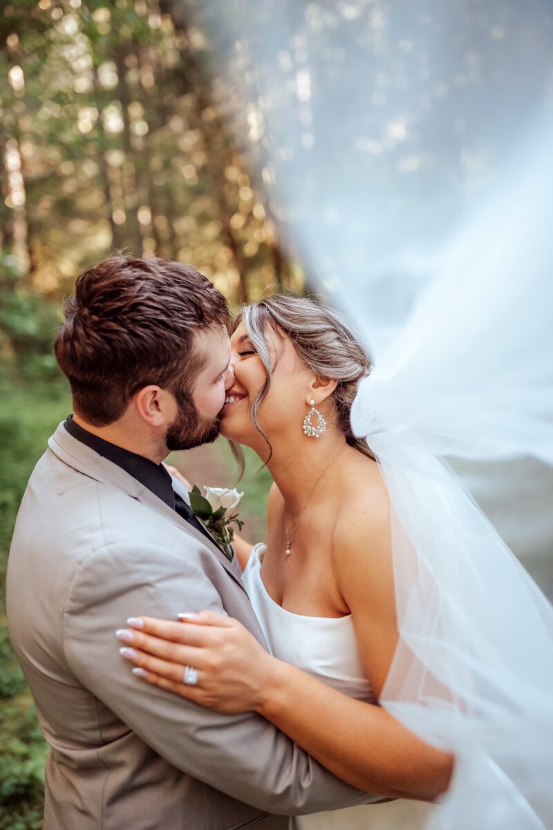real bride posing with her groom in the forest with a dramatic veil photo