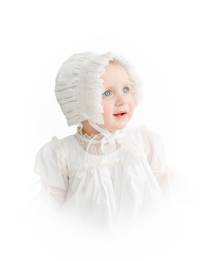 white vignette portrait of a little girl in a white bonnet