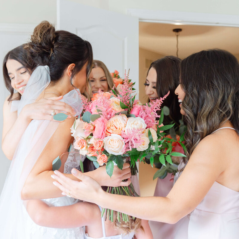 Ottawa wedding photos of a bride hugging her bridesmaids dressed in pink dresses