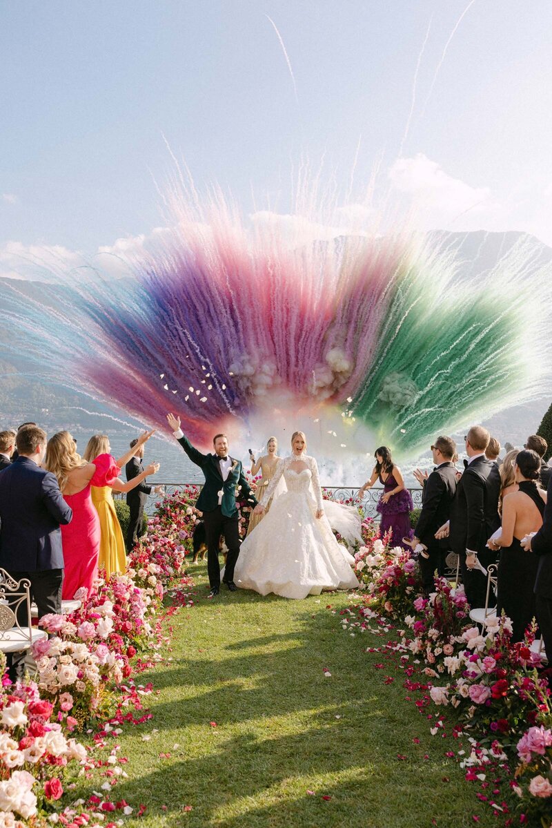Couple walking down the aisle with color bombs exploding in the sky at Villa Balbiano Lake Como,