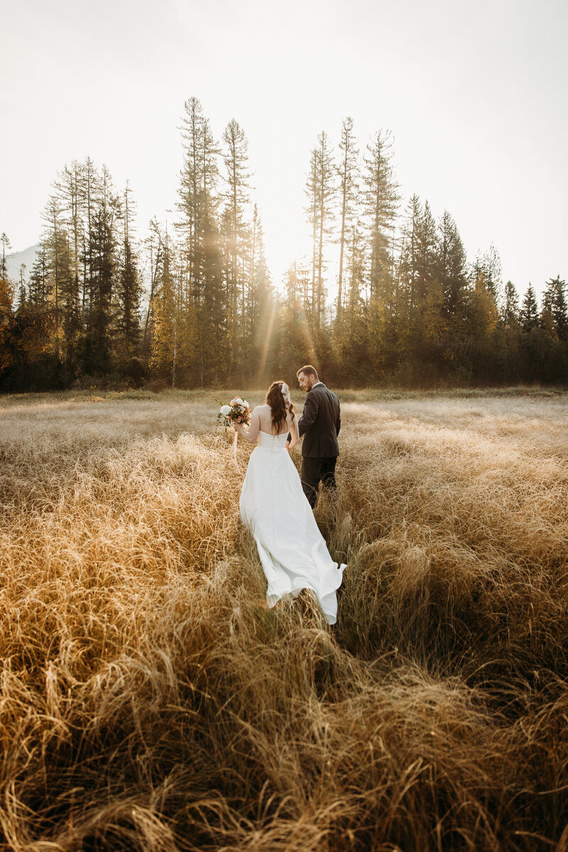 Couple holding hands walking together in fields of montana
