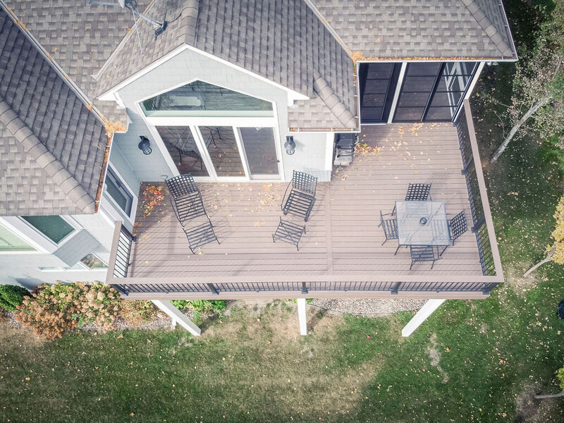 Aerial view of a TimberTech deck with a sliding glass door into the house on the left and a swinging door into the three-season porch on the right. 