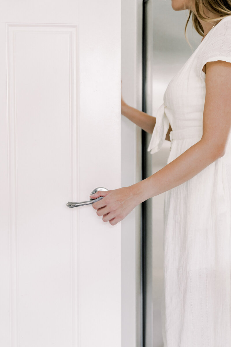 Woman in a white dress opening a door