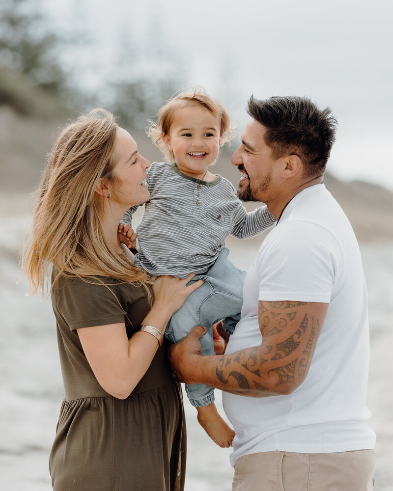 Little boy with Mum and Dad during fun family portrait session at Ruakaka Beach